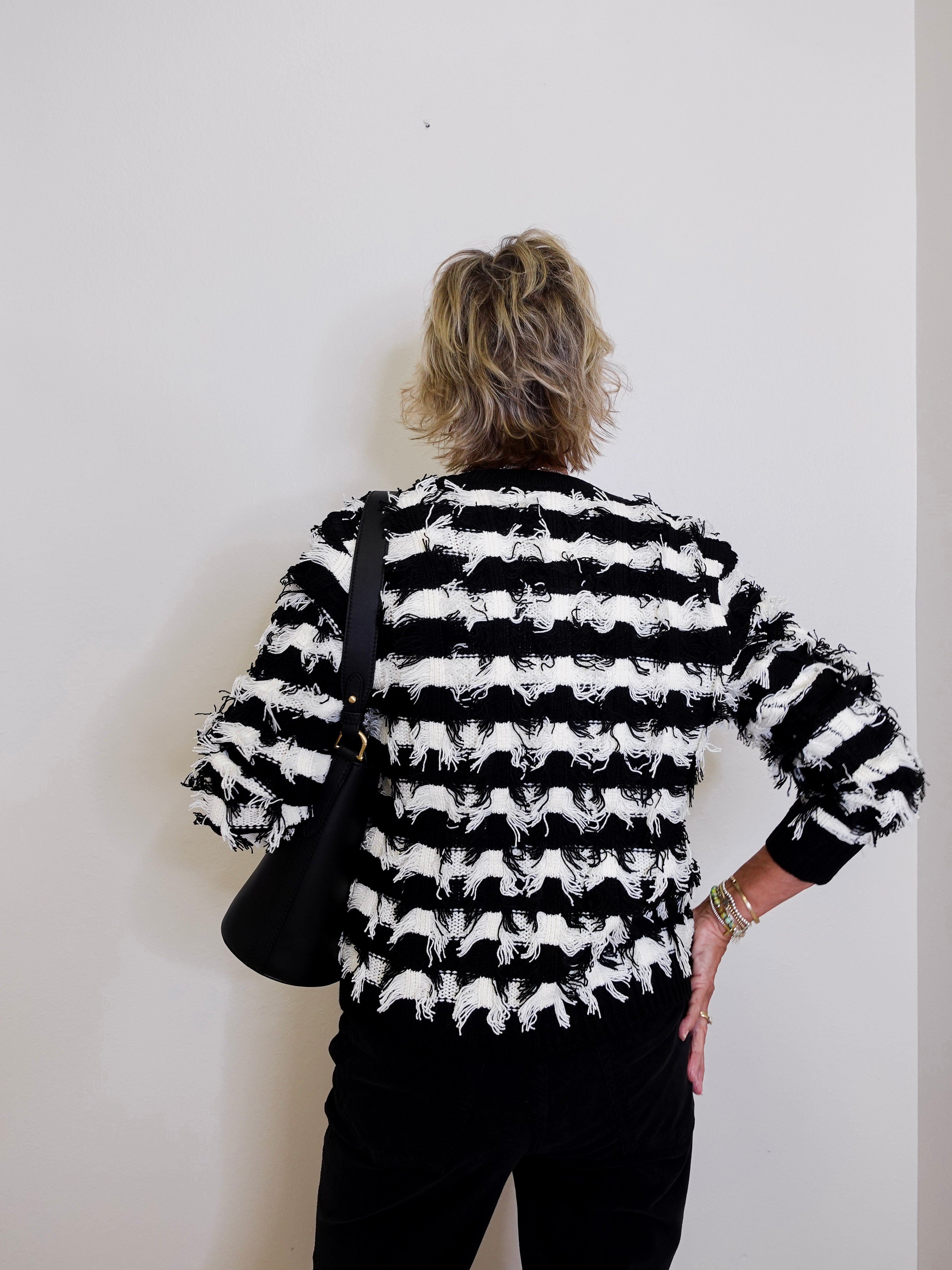 Person wearing a black and white striped sweater with a plain background