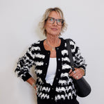 Woman wearing a black and white patterned jacket against a plain background
