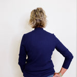 Person wearing a navy blue sweater and jeans against a white background