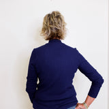 Person wearing a navy blue sweater and jeans against a white background