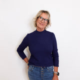 Person wearing a navy sweater and blue jeans against a white background