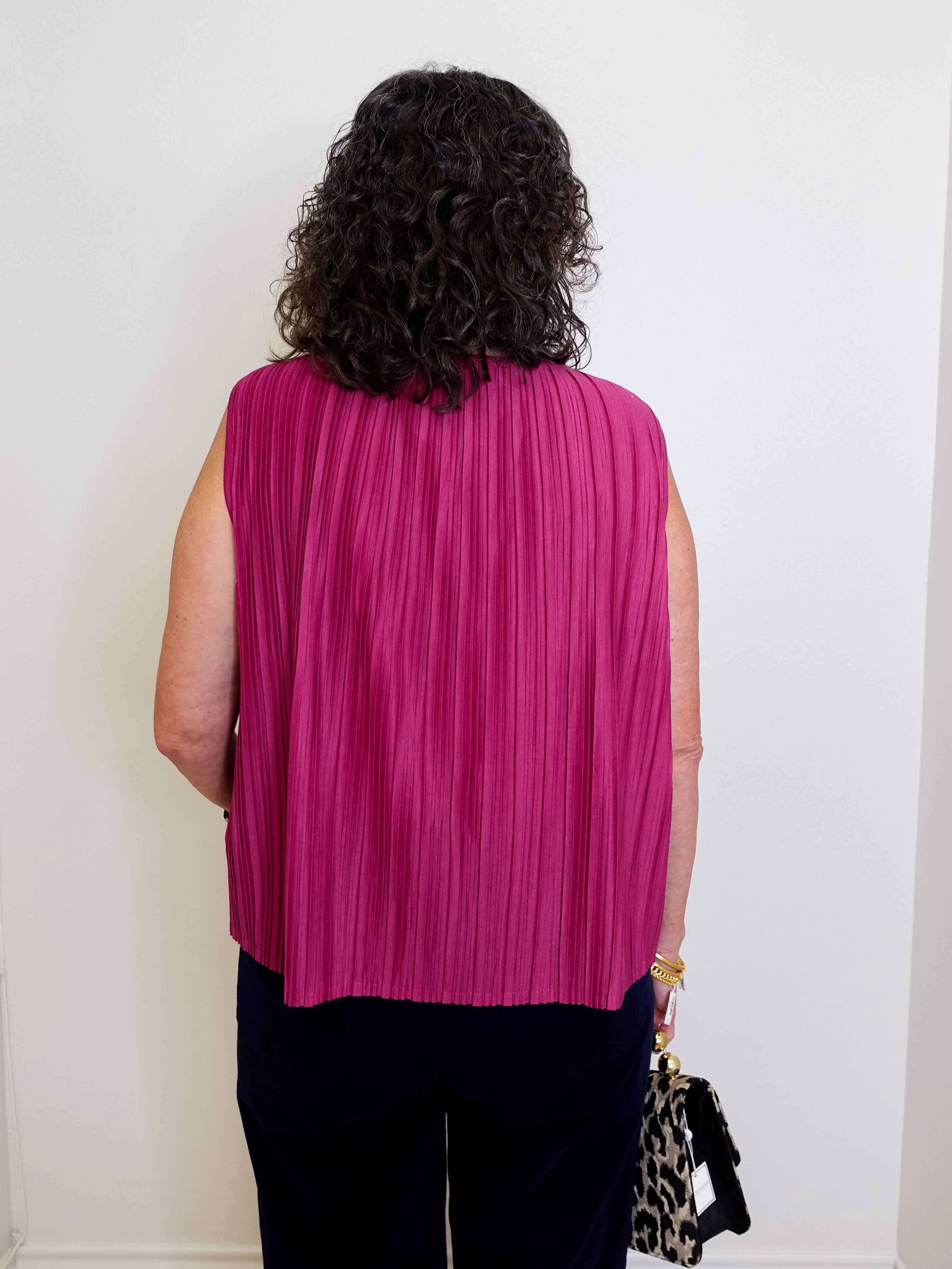 Person wearing a pink pleated top against a white wall