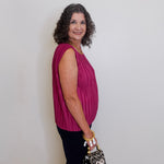 Woman in a pink top holding a leopard print bag against a plain background