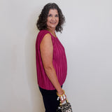 Woman in a pink top holding a leopard print bag against a plain background