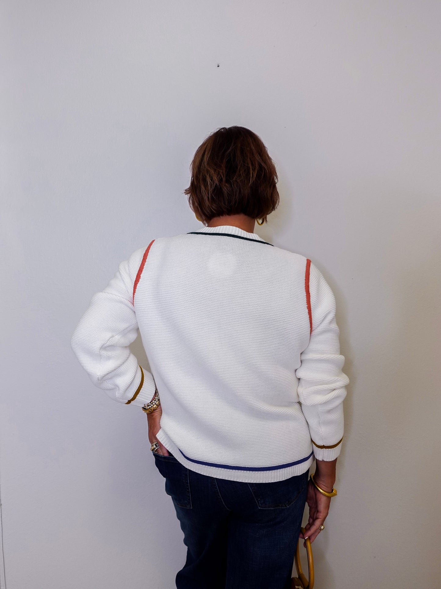Person wearing a white jacket with colorful accents against a plain background
