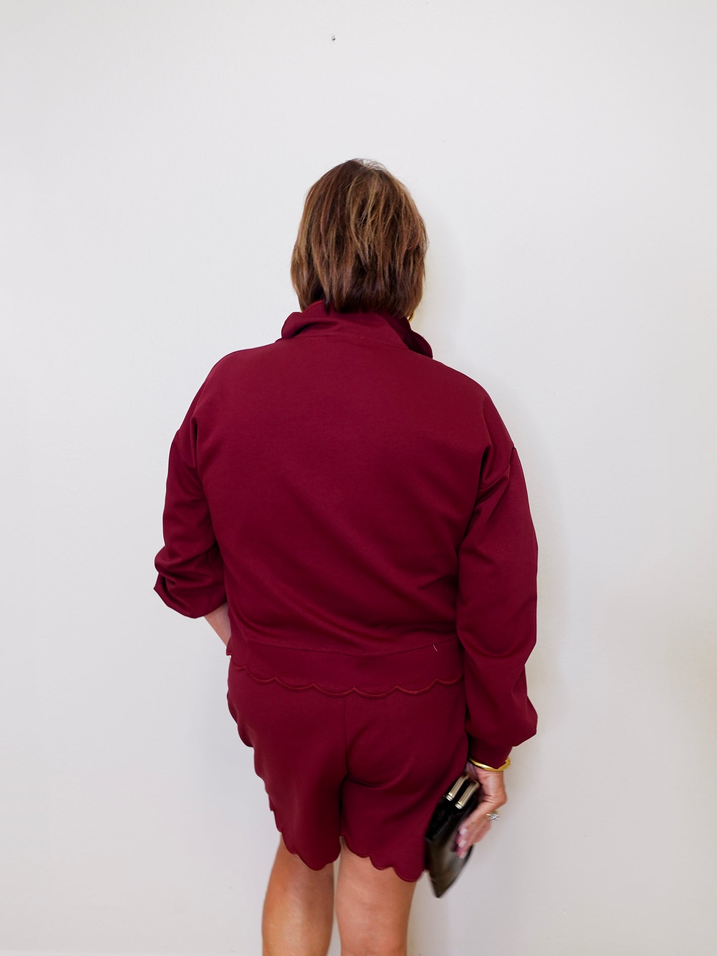 Person wearing a maroon outfit against a white wall