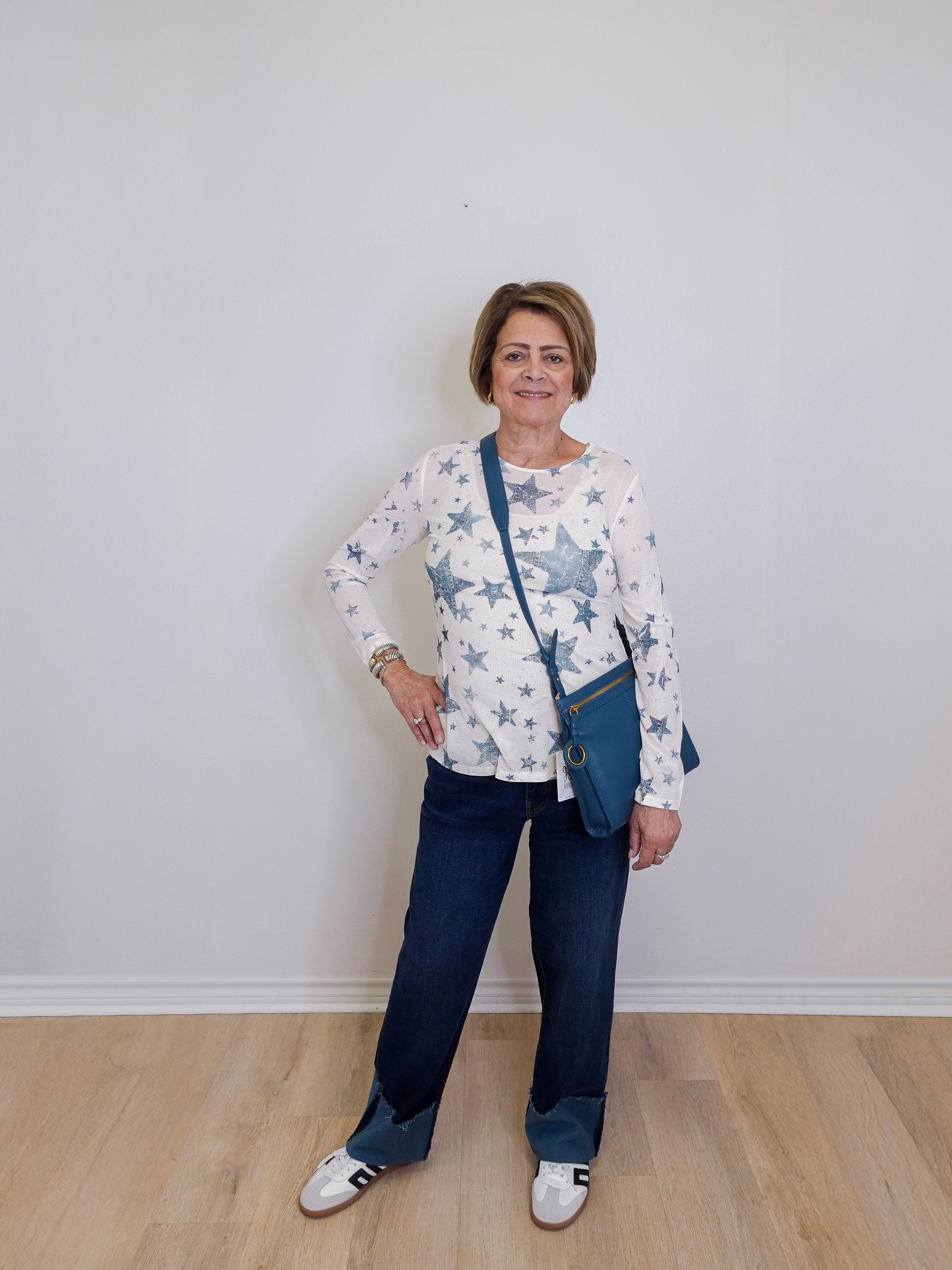 Woman wearing a star-patterned shirt and blue jeans with a white background