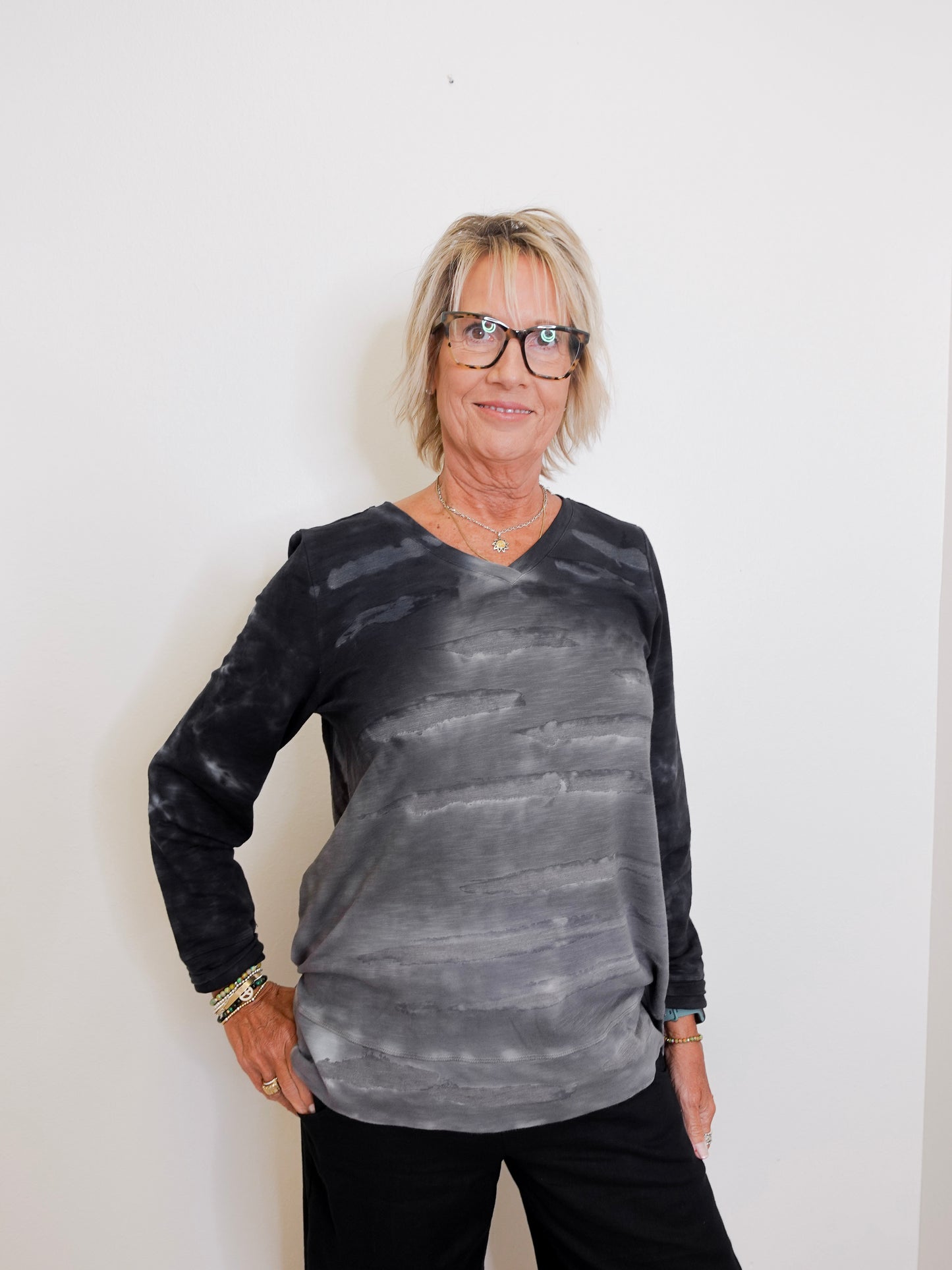 Person wearing a black and gray tie-dye long-sleeve shirt against a white background