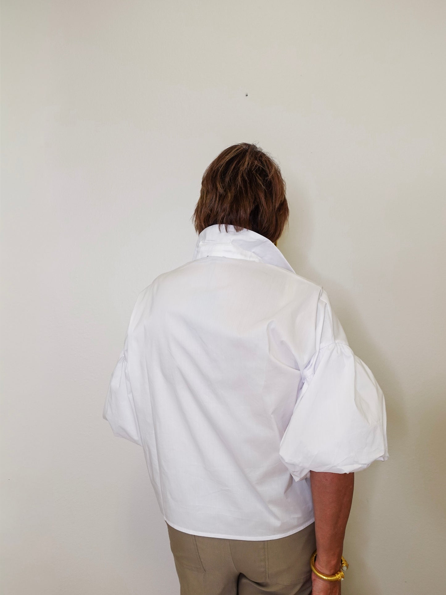 Person wearing a white shirt against a plain background