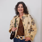Woman wearing a patterned beige jacket against a white background