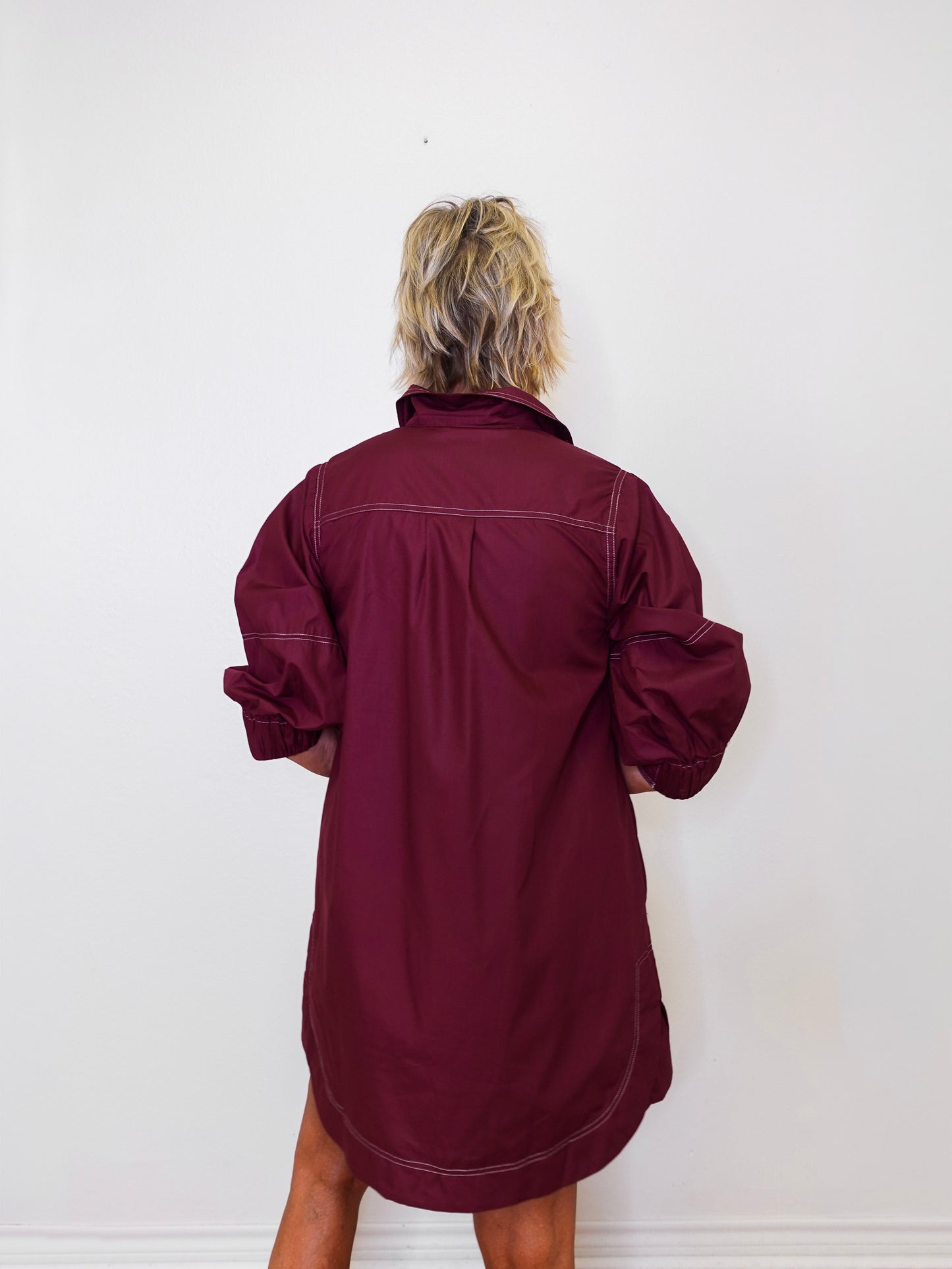 Person wearing a burgundy dress against a white background