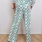 Person wearing a patterned outfit with green wreaths and pink flowers on a white background