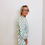 Person wearing a green and pink patterned outfit against a white background