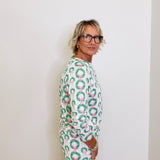 Person wearing a green and pink patterned outfit against a white background