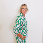 Woman wearing a green patterned outfit against a white background