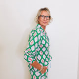 Woman wearing a green patterned outfit against a white background