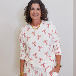 Woman wearing a white outfit with red patterns against a plain background