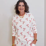 Woman wearing a white outfit with red patterns against a plain background