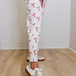 Person wearing white pants with red patterns and white sneakers on a wooden floor.