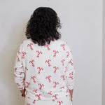 Person wearing a white outfit with red patterns against a plain background