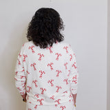 Person wearing a white outfit with red patterns against a plain background