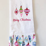 White towel with colorful Christmas ornament design and 'Merry Christmas' text on a light gray background