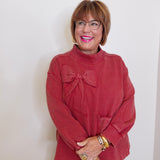 Woman wearing a red sweater with a bow design against a white background