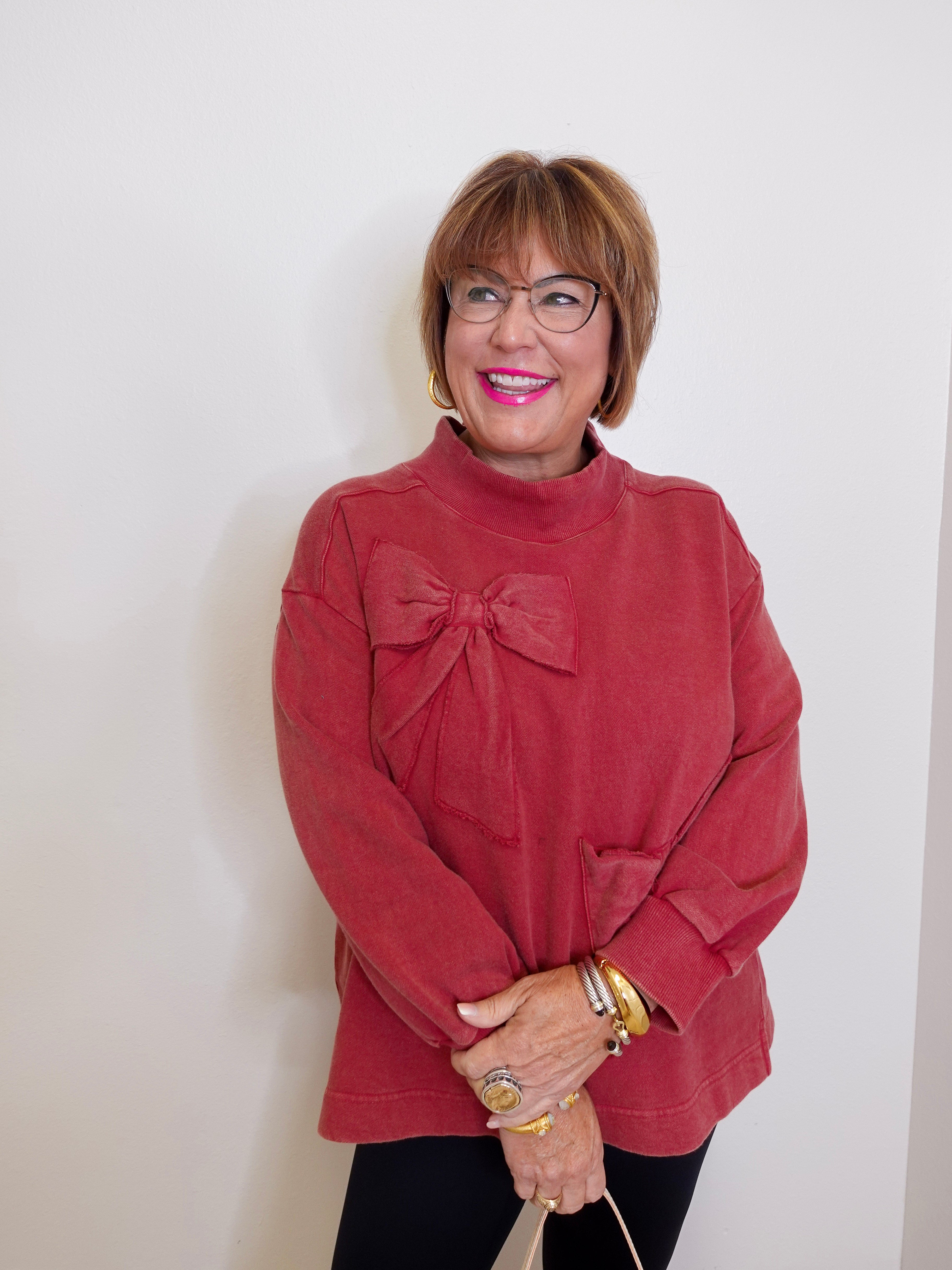 Woman wearing a red sweater with a bow design against a white background