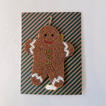 Decorative gingerbread man ornament on a striped card with a plain background