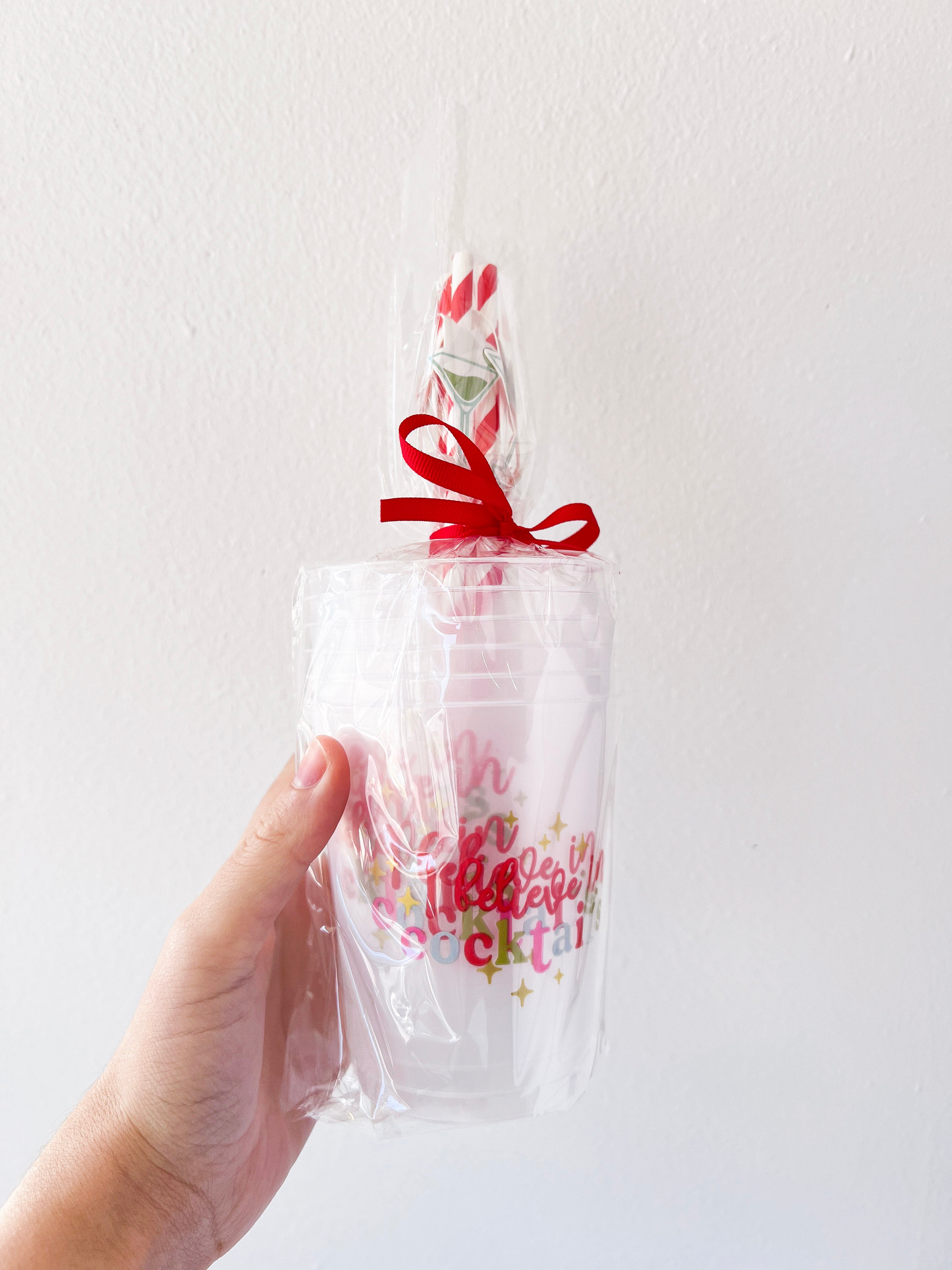 Hand holding a clear plastic bag with colorful text and a red ribbon against a white background