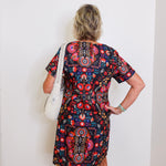 Person wearing a colorful patterned dress against a white wall