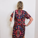 Person wearing a colorful patterned dress against a white wall