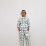 Person wearing a green and white patterned outfit against a white wall.