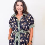 Woman wearing a dark floral dress with a white background
