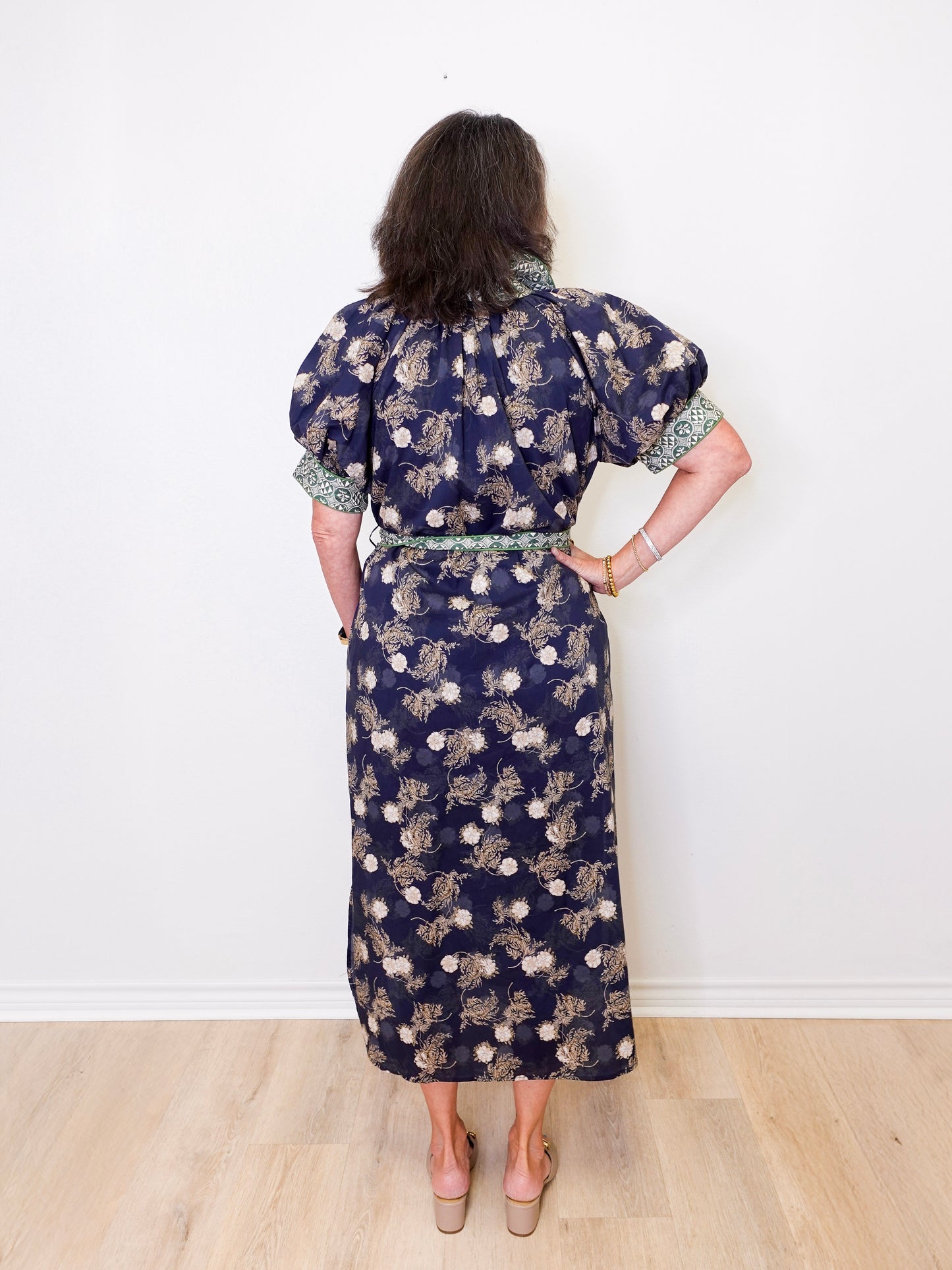 Woman wearing a floral dress with a white wall background