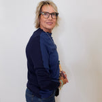 Person wearing a navy blue sweater and jeans against a white background