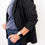 Person wearing a black pinstripe blazer over a blue shirt with a white background