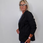 Person wearing a black pinstripe blazer against a plain background