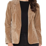 Woman wearing a brown corduroy blazer over a black top on a white background