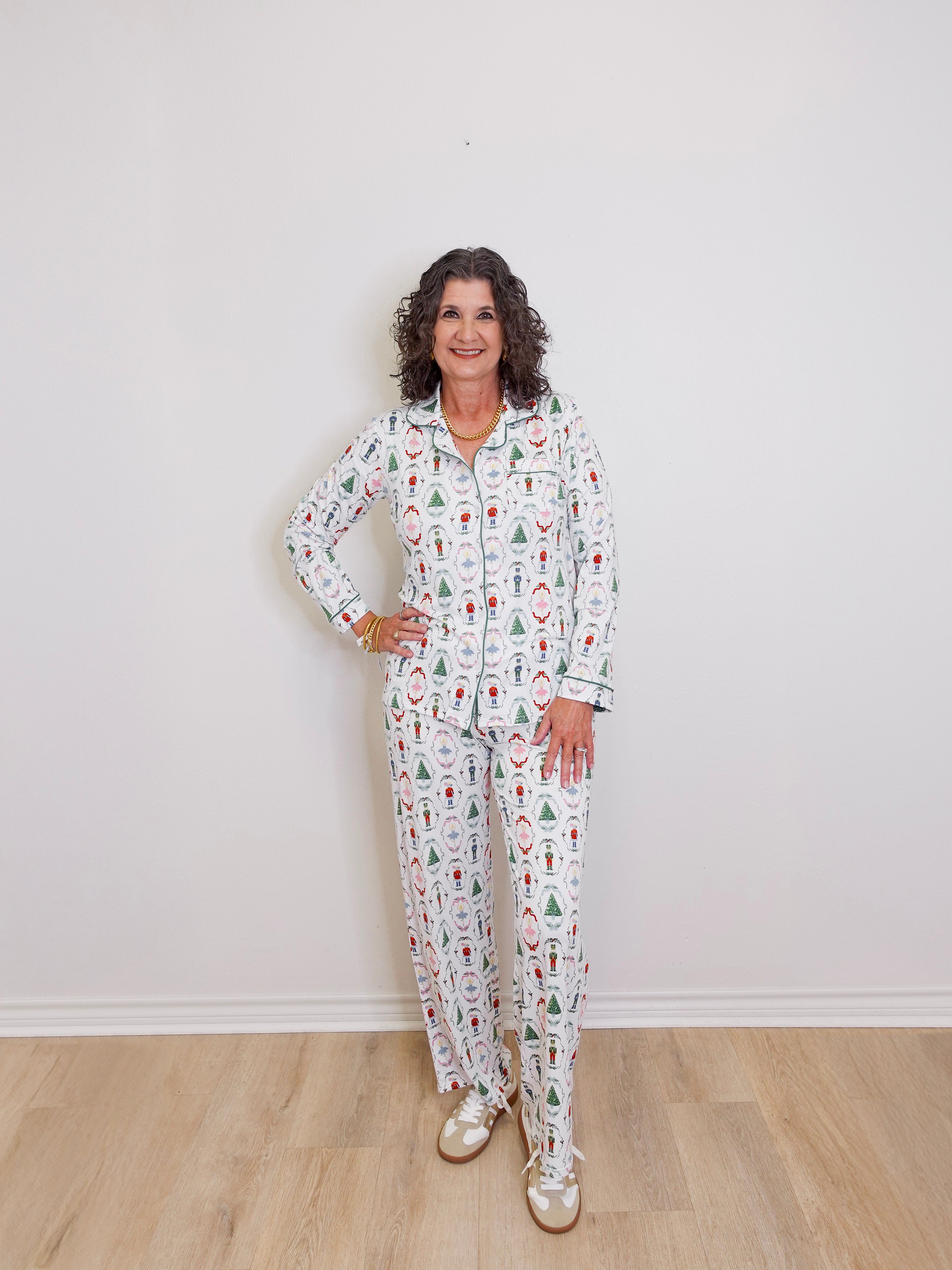 Woman wearing a patterned pajama set against a white wall.