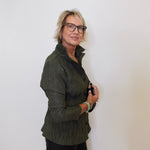 Person wearing a green jacket and black pants against a white background