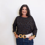 Woman wearing a leopard print top and jeans with a white background