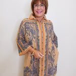 Woman wearing a patterned coat against a white wall