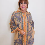 Woman wearing a patterned coat against a white wall