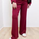 Person wearing a maroon tracksuit with white shoes on a light wooden floor.