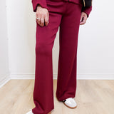 Person wearing a maroon tracksuit with white shoes on a light wooden floor.