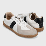 Pair of white and beige sneakers with black accents on a light gray background