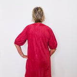 Person wearing a red dress against a white wall
