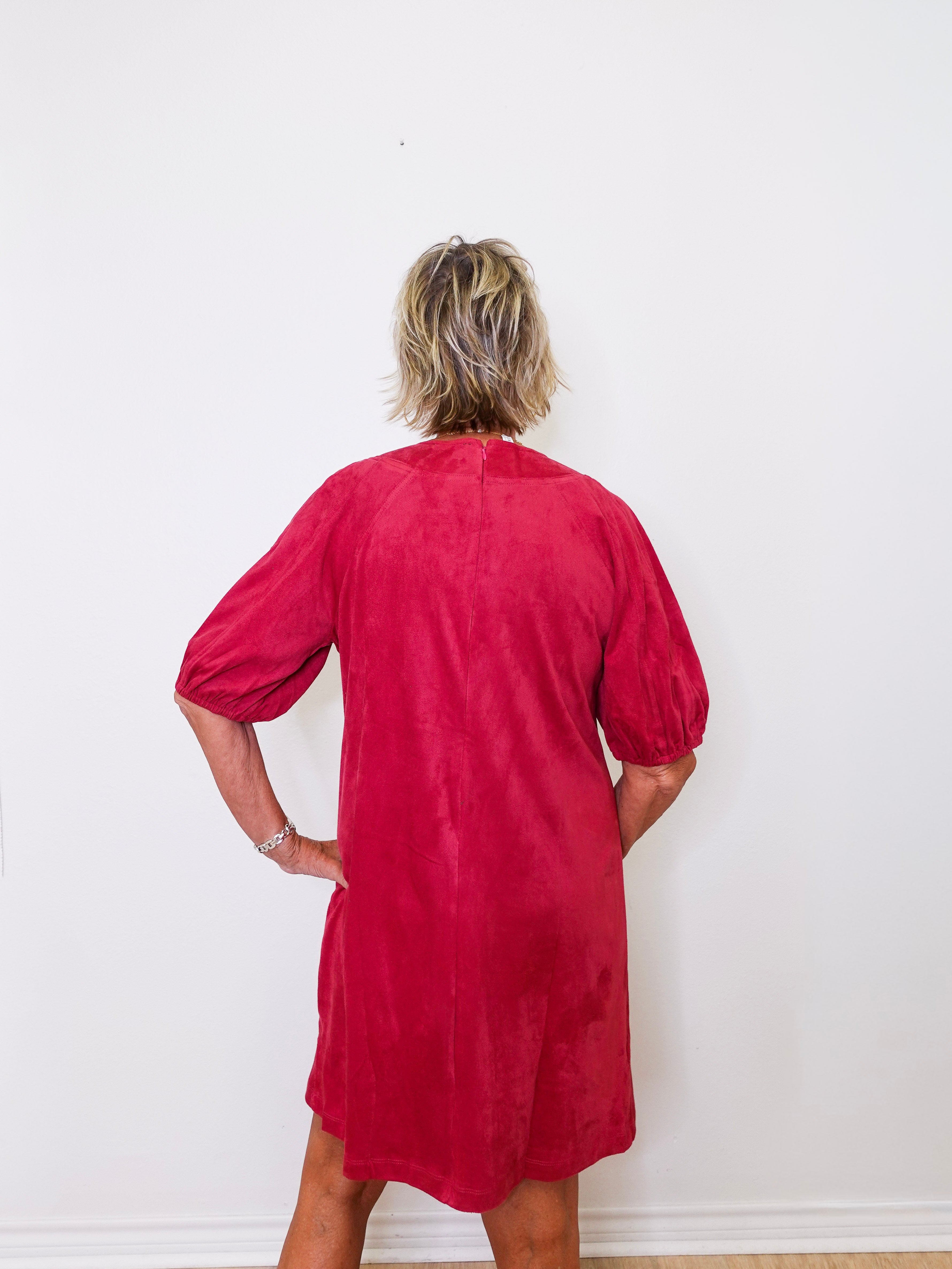 Person wearing a red dress against a white wall