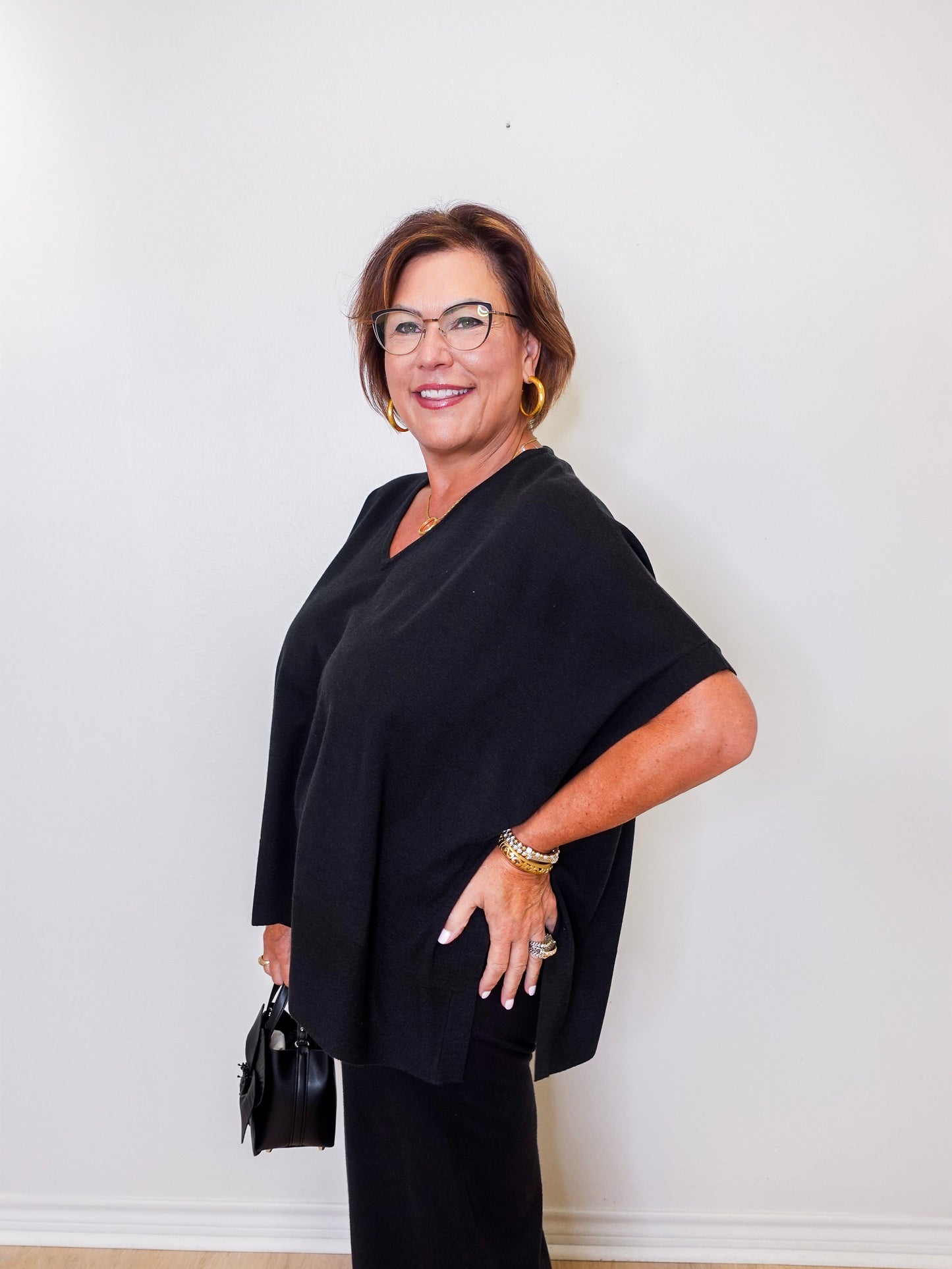 Woman wearing a black outfit with glasses against a white wall